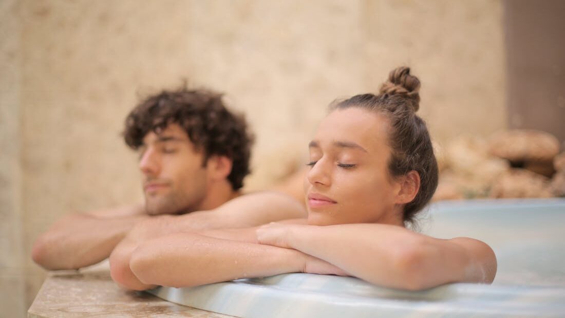 Couple resting in an outdoor hot tub, leaning on the edge and enjoying a quiet, private soaking experience